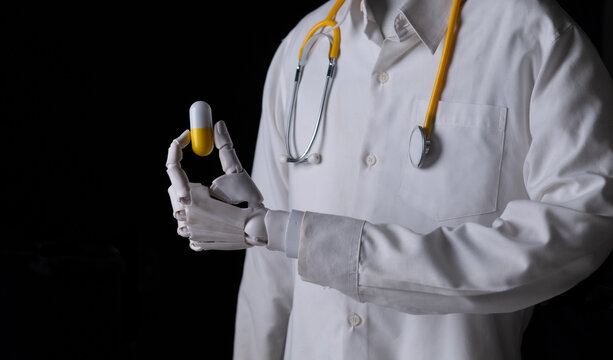 Robot doctor hand holding a yellow and white capsule pill close up.