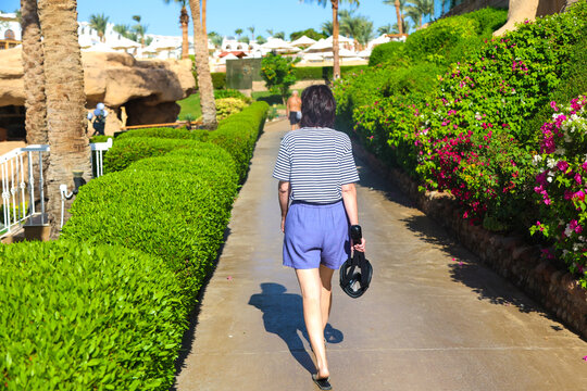 woman returns from the beach, carrying a snorkeling mask in her hand, embodying the spirit of summer adventures and ocean exploration.