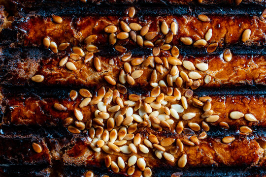 Macro texture of grilled baked pastry surface with sesame. Closeup pattern of golden brown baked pie or bread crust with toasted sesame seeds. Textured backdrop for bakery marketing culinary recipes