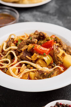 Beef lagman close up with glossy noodles, red pepper and tender meat in spiced broth for recipe