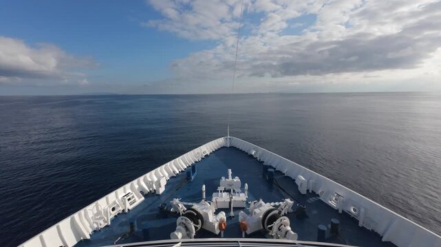 Forward deck view of vessel navigating calm waters toward islands