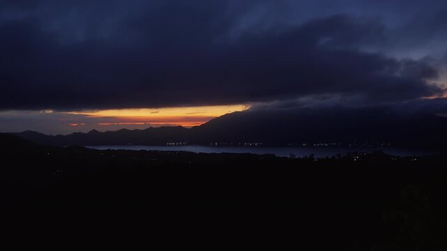Dark Clouds Drifting Above Mount Abang and Lake Batur at Sunrise, Wide Angle View of Volcanic Highlands With Glowing Sky and Tranquil Natural Beauty