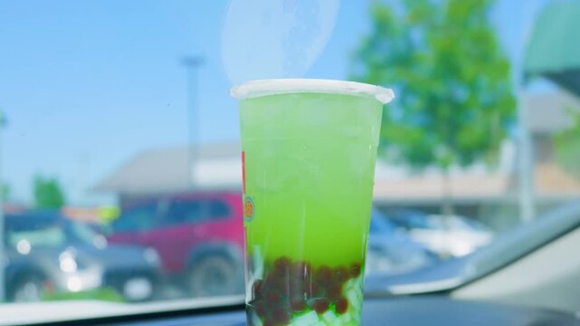Iced green bubble tea with tapioca pearls on car dashboard