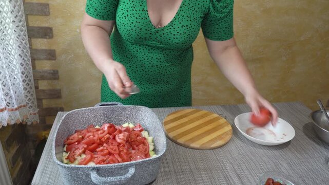 woman cutting fresh tomatoes for stew, Adding chopped tomatoes into a casserole pot