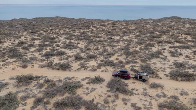 Suv pulls a teardrop camper trailer across sandy terrain during an off road adventure in Guerrero Negro Baja California Mexico