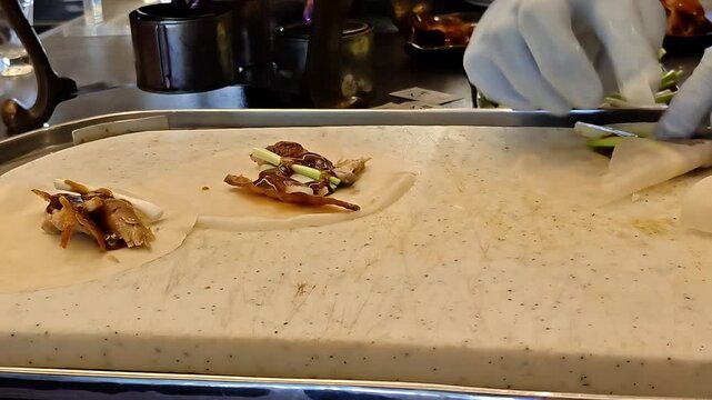 Chef hands folding and rolling Peking duck pancakes, Chinese Cantonese Food Cuisine, Poultry Meat, Restaurant Meal Preparation, Eye Level Closeup