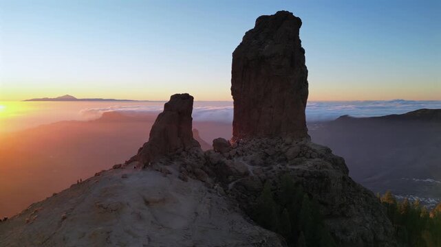 Breathtaking aerial shot orbiting the Roque Nublo monolith in Gran Canaria. The stunning landscape is bathed in the warm sunset light