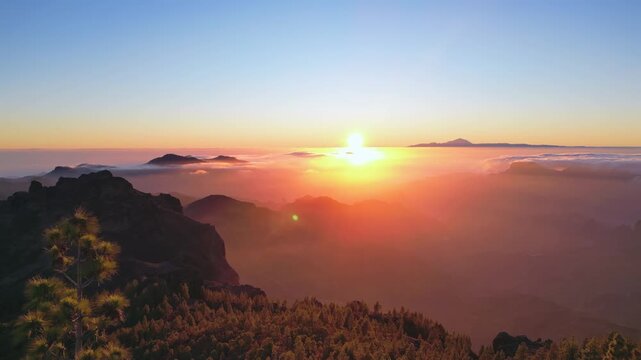 Stunning aerial view flying over the mountains of Tejeda at sunset. The sun shines through the clouds creating a magical landscape. Gran Canaria