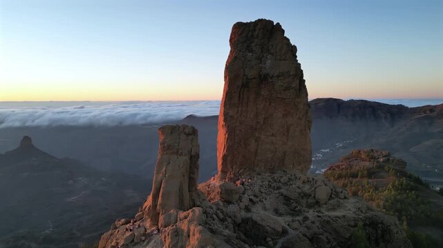Spectacular aerial view of the volcanic rock Roque Nublo during sunset. Majestic mountain landscape of Tejeda, Gran Canaria, above the clouds