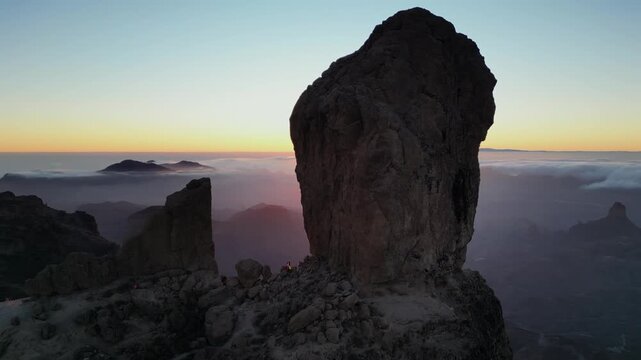 Aerial view of the iconic Roque Nublo volcanic rock in Tejeda, Gran Canaria. Majestic mountain landscape above the clouds during a vibrant sunset
