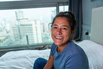 Fototapeta premium Woman smiling relaxing on bed in hotel room