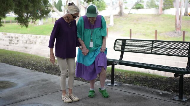 Mature daughter spends time with her elderly mother, practicing dance in the park, enjoying each others company, and sharing stories.