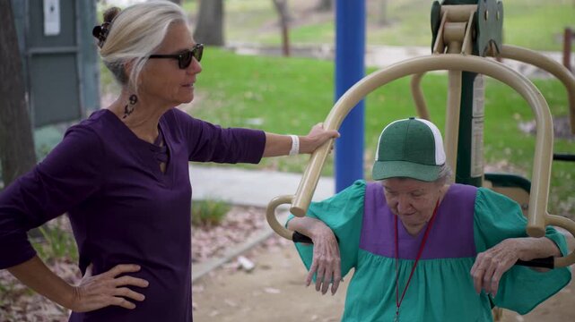 Happy mature daughter shares stories with her elderly mother during their visit at the park, enjoying each others company and laughter