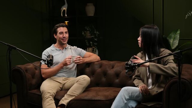 Two people having an interesting conversation during a podcast interview sitting on a sofa