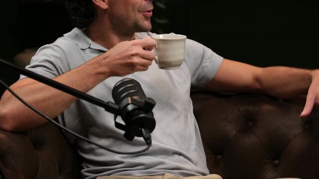 Young man gesturing and talking while recording a podcast in a professional studio
