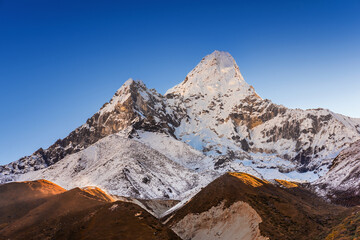 Obraz premium Snowy mount Ama Dablam illuminated by rising sun. Sunrise iew from Pangboche village on Everest base camp trek in Nepal.