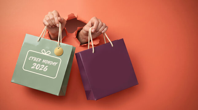 Hands Holding Colorful Shopping Bags with New Year 2026 Gift Bag on Orange Background, Holiday Retail Sale Banner