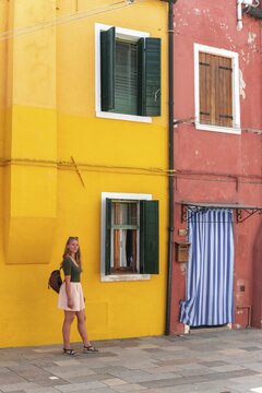 Young woman in front of colorful house, colorful house facades, tourist on Burano island, Venice, Veneto, Italy