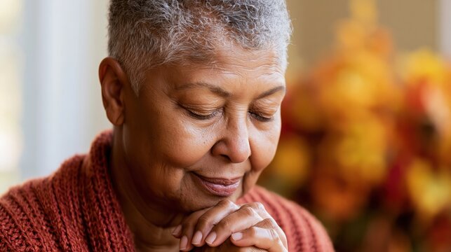 Elderly Black woman in meditation with hands clasped and eyes closed