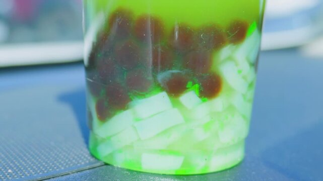 Macro detail of green bubble tea with boba pearls and jelly