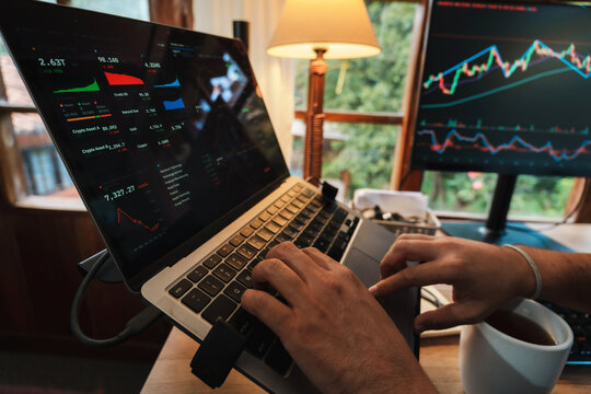 Trader hands working with Stock chart on Multiple Screens