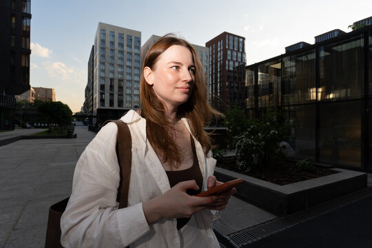 A woman checks her phone in a modern urban courtyard
