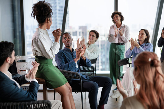 Diverse team applauds a colleague in a modern office meeting