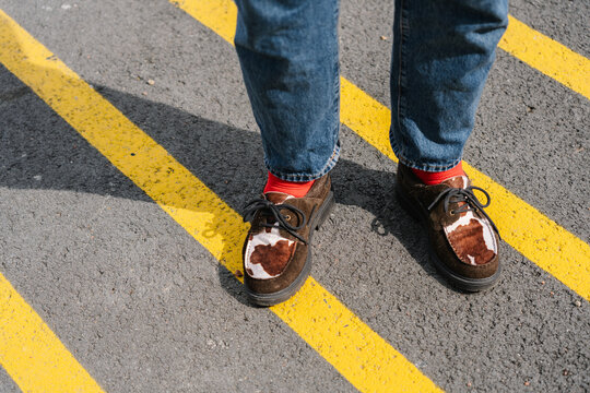 Brown shoes with red socks standing on bright yellow road