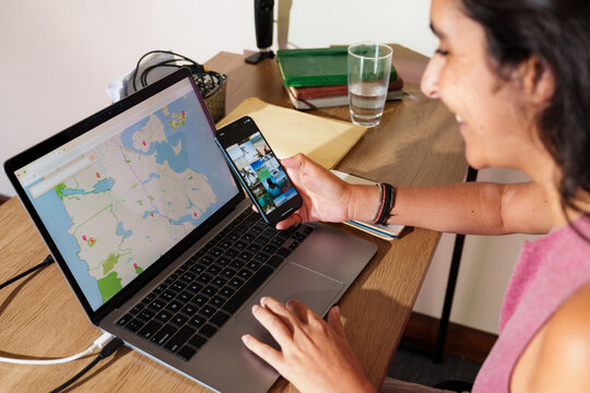 Woman Planning a Trip with Laptop and Smartphone at Home