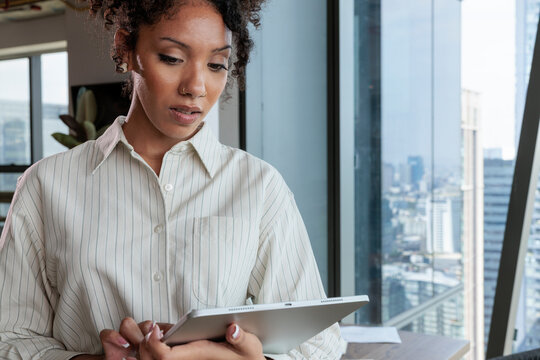 Woman with digital tablet in modern office setting.