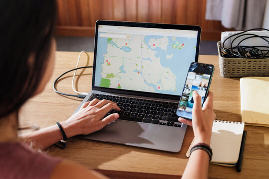 Woman Planning a Trip with Laptop and Smartphone at Home