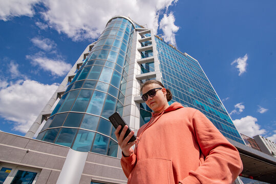 Teenage guy looking at a phone against the blue sky. 