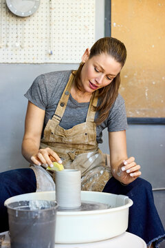 A Woman Works With Clay on a Pottery Wheel