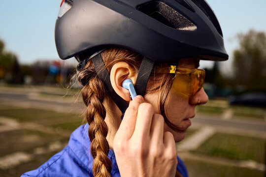 Cyclist Prepares for Ride While Adjusting Earbud