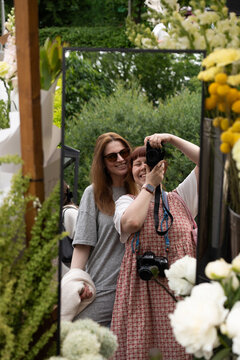 Friends share a camera amid blooming white hydrangeas
