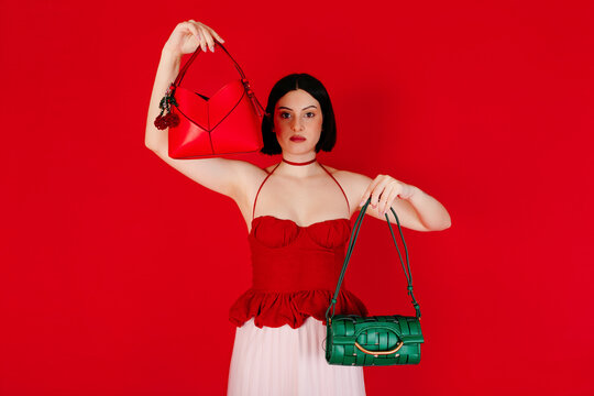 Stylish woman holding red and green handbags
