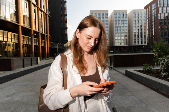 A woman checks her phone in a modern urban plaza