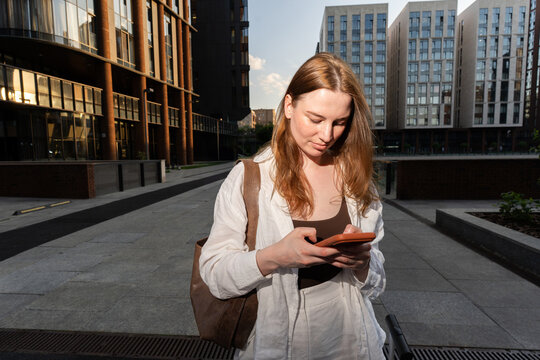 A woman checks her phone in late afternoon sunlight