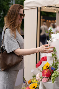 A woman selects fresh flowers from a market stall display