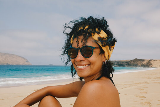 Woman smiling on the beach with waves in the background