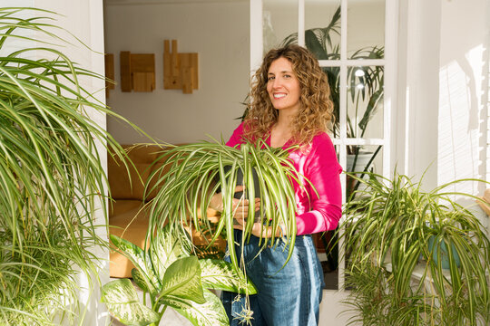 Woman tending to indoor houseplants in bright, cozy balcony space