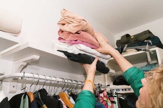 Woman organizes clothes in a bright fitting room for daily life