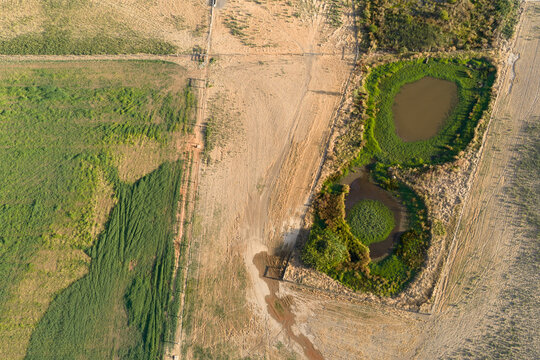 Fences around grass encircled dams and dry farm paddocks