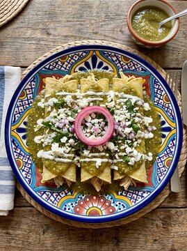Bird's-Eye View of Three Rolled Green Enchiladas with Salsa Verde, Crema, Queso Fresco, and Pickled Red Onion Ring

