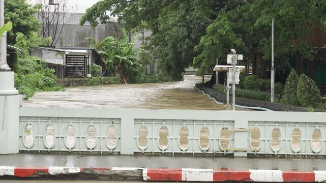 view of highest level of water flooded in canal over the bothside of canel's bankside while water flowing through phuket city old town after heavy raining