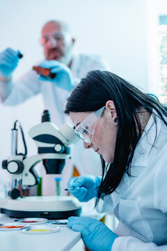 Dark-Haired Female Scientist Uses Loupe to Inspect Colorful Pigment Samples at Lab Bench 