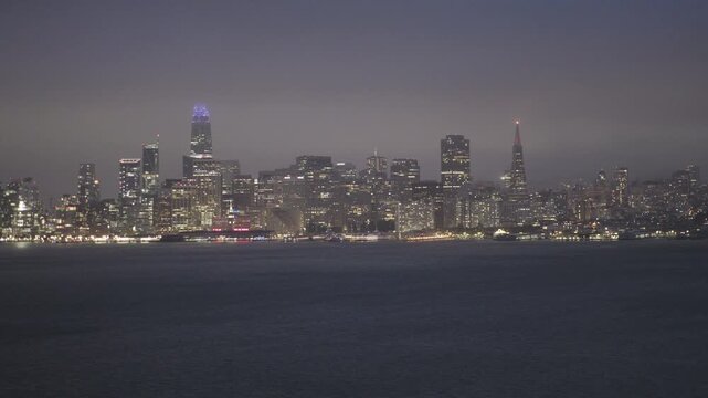 Sparkling San Francisco Skyline at Night Across Calm, Misty Bay - Wide, Tracking Shot