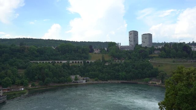 Rhine Falls Switzerland. Panoramic View of Scenic River Bend, High-Rise Buildings, Lush Green Forest and Cloudy Summer Sky