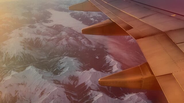 Airplane wing over glacier valley in Canadian Rockies near Banff, golden light aerial view