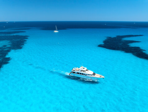Aerial drone view of floating luxury yacht in blue sea on sunny day. Summer vacation. Mallorca island, Spain. Top down view of boat, sea, turquoise water. Travel. Tropical landscape. Yachting. Cruise